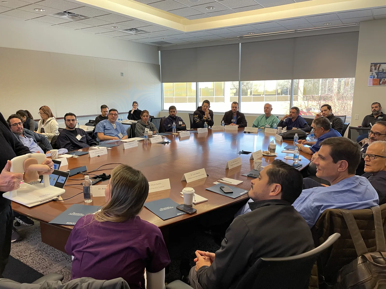 Course attendees seated around a boardroom table during the didactic session, with an anatomical model on the table